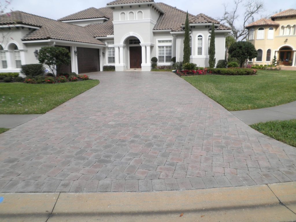 Long paver driveway at a large stucco home, grey and flat