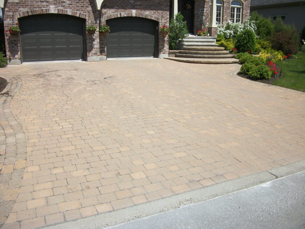 Wide paver driveway at a brick home, faded and patchy