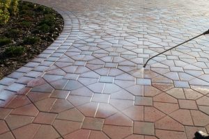 Flagstone-pattern paver surface being rinsed down with a hose