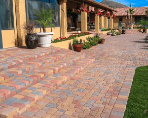 Multi-coloured brick paver driveway beside a yellow Mediterranean-style house