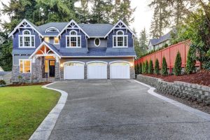 Large blue-grey house with a three-car garage and a wide concrete driveway