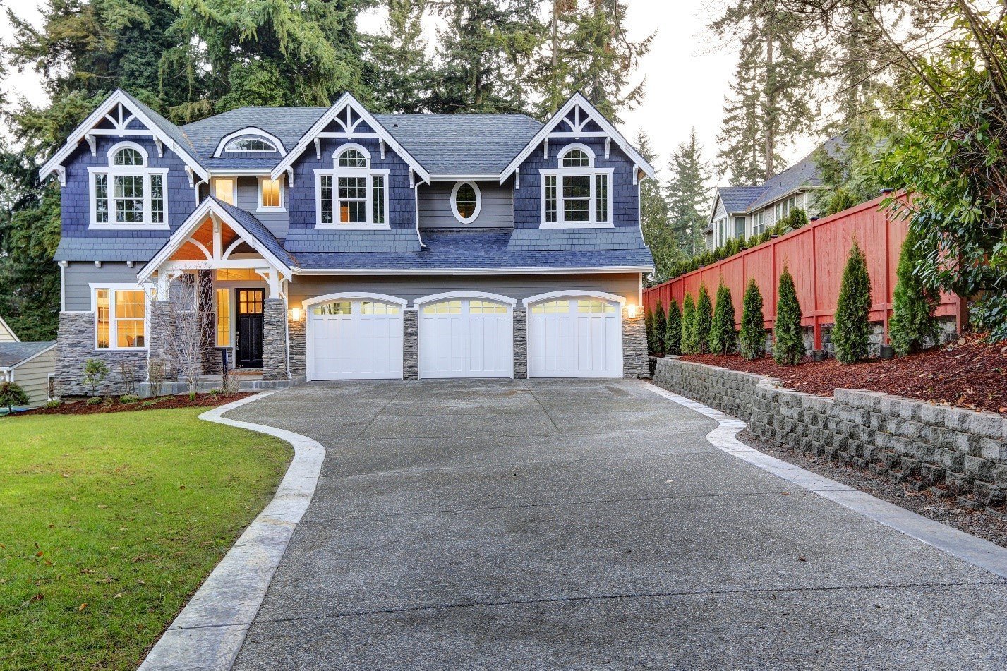 Large blue-grey house with a three-car garage and a wide concrete driveway