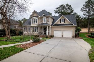 Two-storey house with a wide concrete driveway in autumn