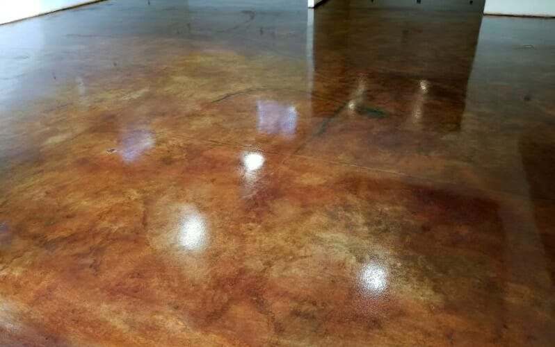 Glossy stained concrete floor in mottled amber and brown, reflecting the light