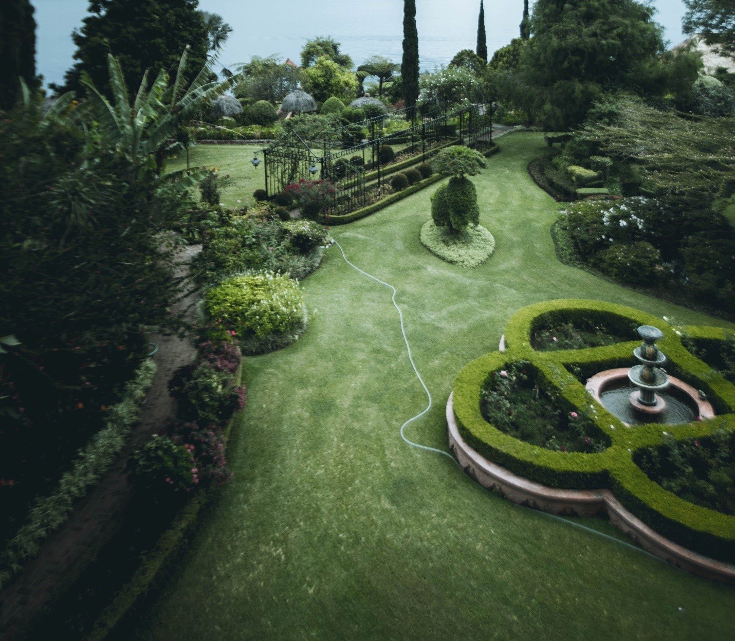 Formal garden from above, with clipped hedges, a circular fountain bed and lawn