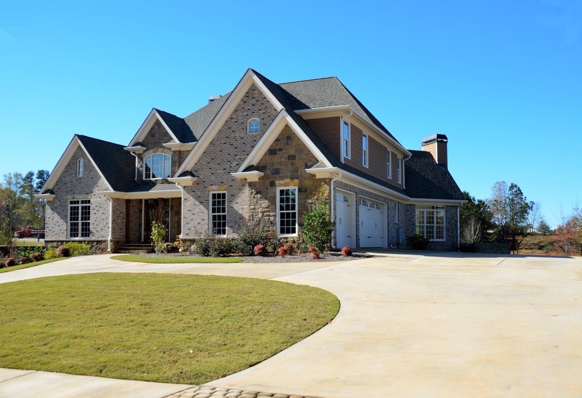 Stone-fronted house with a curving concrete driveway and lawn