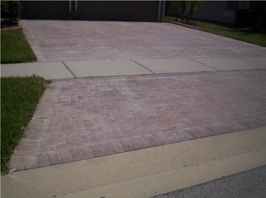 Brick paver driveway apron meeting a concrete sidewalk, the sealer faded and whitened