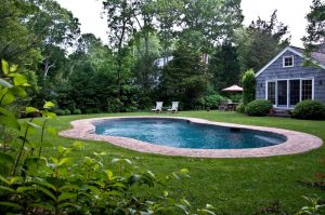 Kidney-shaped swimming pool with a paver surround in a lawned back garden