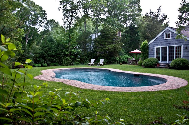 Kidney-shaped swimming pool with a paver surround in a lawned back garden