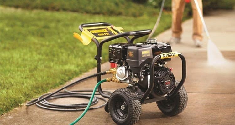 Petrol pressure washer on a lawn while a driveway is being washed
