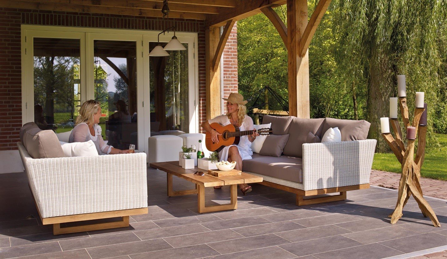 People seated on white sofas in a covered outdoor lounge under a timber pergola