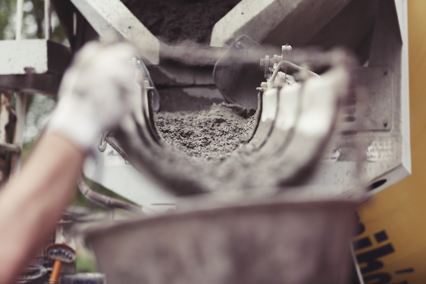 Gloved hands scooping wet concrete mix from a bucket