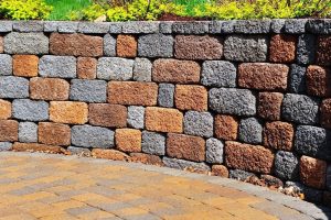 Retaining wall of multi-coloured blocks above a curved paver path