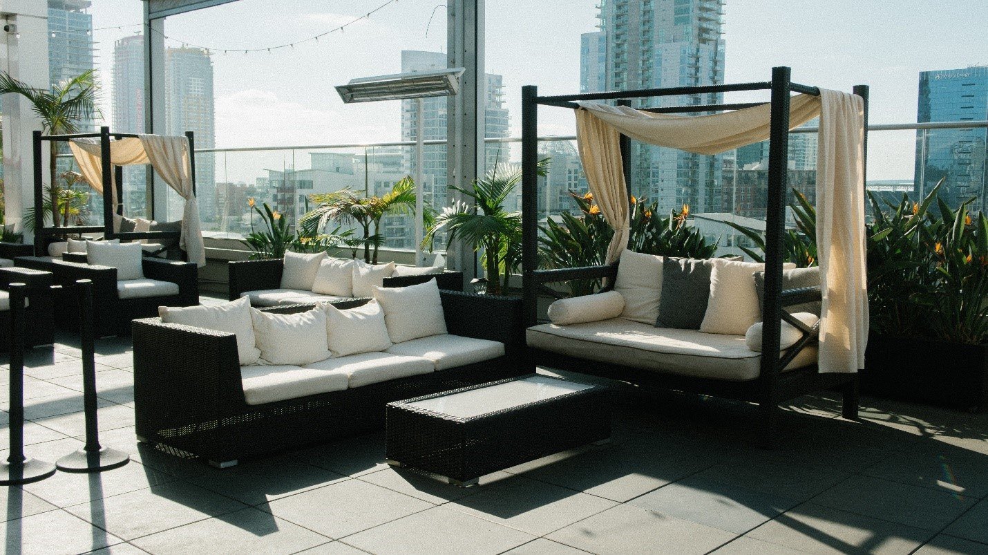 Rooftop terrace with black cabanas and cushioned seating, city towers behind