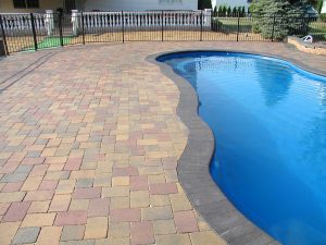 Sealed paver pool deck surrounding a curved swimming pool