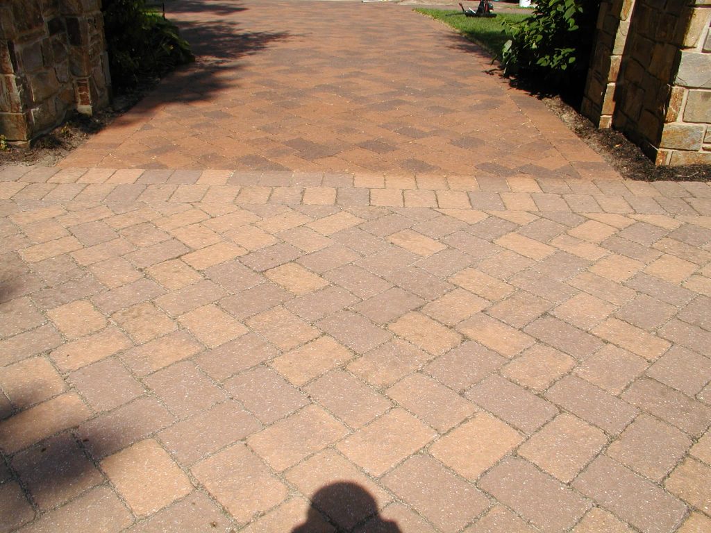 Sealed paver driveway curving toward a stone building