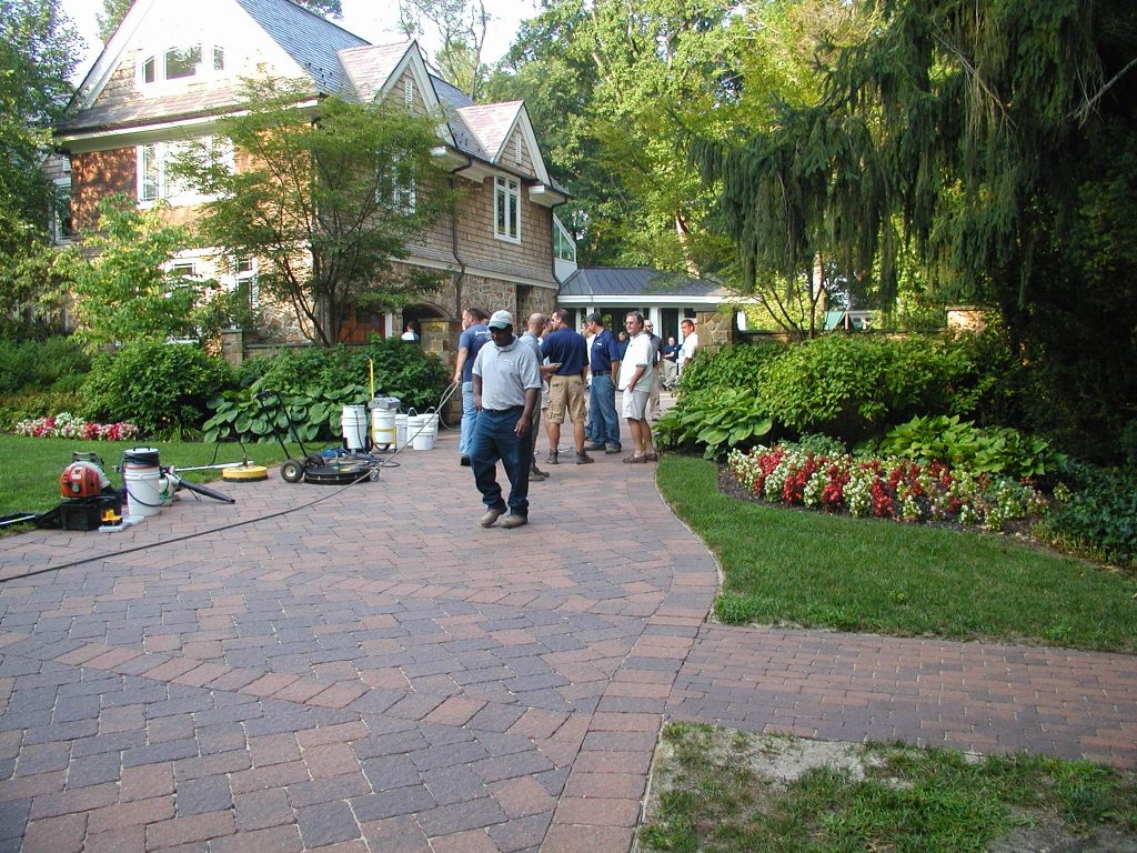 Trainees walking a paver path beside a large stone house