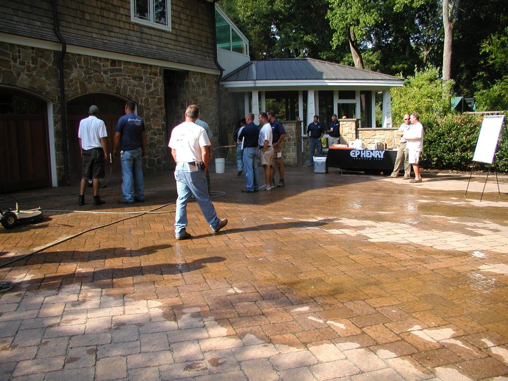 Contractors working across a wet paver driveway at a training day