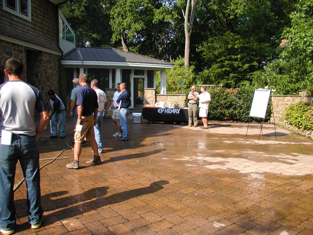 Contractors watching a paver driveway being cleaned at a training day