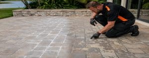 Contractor pointing out white efflorescence and peeling sealer on a paver patio